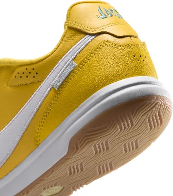Gelber Skateschuh mit weißem Streifen und Gummisohle.