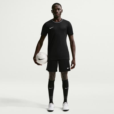 Ein Mann im schwarzen Fußballtrikot und Shorts hält einen Ball. Ein Mann im schwarzen Fußballtrikot und Shorts hält einen Ball.