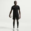 Ein Mann im schwarzen Fußballtrikot und Shorts hält einen Ball.