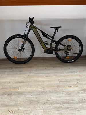 Grünes E-Bike mit Federung und schwarzen Rädern auf Holzboden.