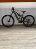 Grünes E-Bike mit Federung und schwarzen Rädern auf Holzboden.