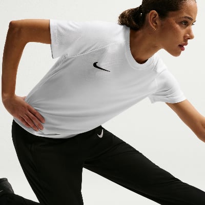 Eine Frau in einem weißen Nike-T-Shirt und schwarzer Hose dehnt sich.