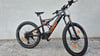 Ein schwarzes KTM E-Mountainbike mit orangefarbenen Akzenten steht auf Schotter.