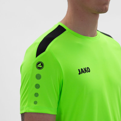 Ein Mann in einem neongrünen T-Shirt mit JAKO-Logo auf der Brust. Ein Mann in einem neongrünen T-Shirt mit JAKO-Logo auf der Brust.
