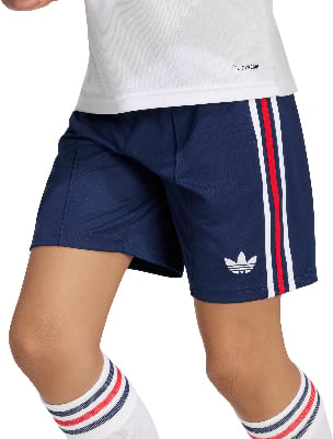 Ein Kind trägt eine dunkelblaue Shorts mit weißem Adidas-Logo und roten Streifen.