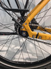 Detail eines gelben Fahrrad-Hinterrads mit Kette und Bremsscheibe.