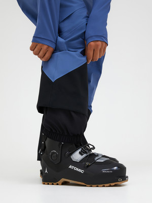 Schwarze Atomic Skischuhe mit blauen Skihosen und Gamaschen. Schwarze Atomic Skischuhe mit blauen Skihosen und Gamaschen.
