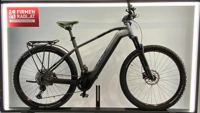 Graues Cube E-Bike mit Gepäckträger und Schutzblechen auf dunklem Ständer. Graues Cube E-Bike mit Gepäckträger und Schutzblechen auf dunklem Ständer.