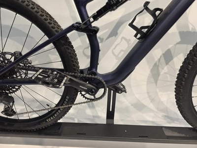 Detail der Rückseite eines dunkelblauen Mountainbikes mit Kette und Pedalen.