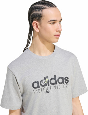 Egy férfi szürke pólóban, Adidas felirattal és koktéllal. Egy férfi szürke pólóban, Adidas felirattal és koktéllal.