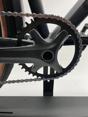 Detail einer Fahrradkurbel mit Kettenblatt und Kette.
