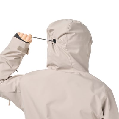 Rückseite einer Person in einer beigen Kapuzenjacke, die eine Kordel zuzieht. Rückseite einer Person in einer beigen Kapuzenjacke, die eine Kordel zuzieht.