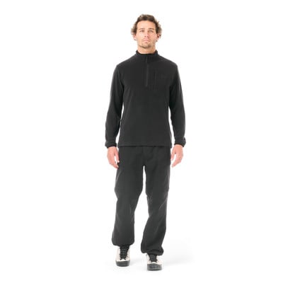Ein Mann in einem schwarzen Fleece-Oberteil und Hose steht vor weißem Hintergrund. Ein Mann in einem schwarzen Fleece-Oberteil und Hose steht vor weißem Hintergrund.