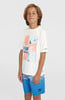 Junge in weißem T-Shirt mit Aufdruck und blauer Hose steht vor weißem Hintergrund.