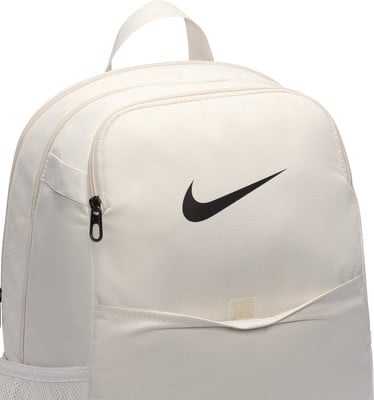 Ein beiger Nike-Rucksack mit schwarzem Logo und Fronttasche. Ein beiger Nike-Rucksack mit schwarzem Logo und Fronttasche.
