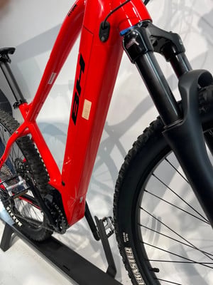 Rotes E-Bike mit schwarzen Details und Federung auf einem Ständer. Rotes E-Bike mit schwarzen Details und Federung auf einem Ständer.