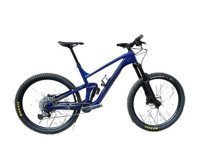 Ein blaues Mountainbike mit Vollfederung, schwarzen Rädern und Maxxis-Aufschriften. Ein blaues Mountainbike mit Vollfederung, schwarzen Rädern und Maxxis-Aufschriften.