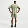 Rückansicht eines Mannes in grünem T-Shirt und Shorts mit Händen in den Hüften.