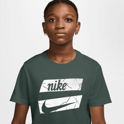 Mädchen in dunkelgrünem T-Shirt mit Nike-Logo und Swoosh. Mädchen in dunkelgrünem T-Shirt mit Nike-Logo und Swoosh.