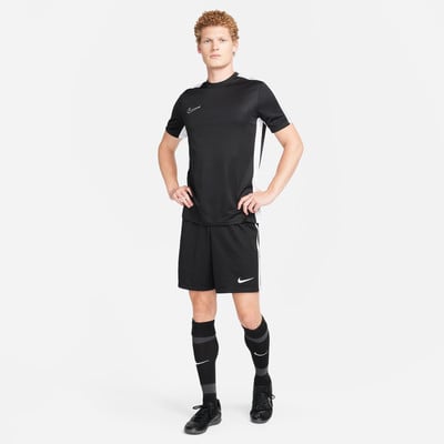 Ein Mann im schwarzen Fußballtrikot und Shorts steht mit den Händen in den Hüften. Ein Mann im schwarzen Fußballtrikot und Shorts steht mit den Händen in den Hüften.