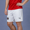 Ein Mann in einem roten Hemd und weißen Shorts mit Puma-Logo und österreichischem Wappen.