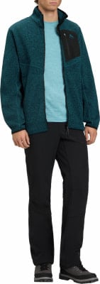 Ein Mann in einem dunkelblauen Fleece-Pullover und schwarzer Hose steht. Ein Mann in einem dunkelblauen Fleece-Pullover und schwarzer Hose steht.