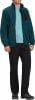 Ein Mann in einem dunkelblauen Fleece-Pullover und schwarzer Hose steht.