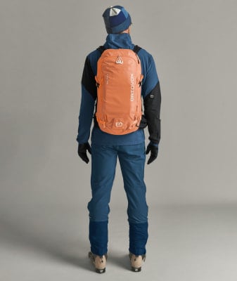 Ein Mann in Skibekleidung mit einem orangefarbenen Rucksack. Ein Mann in Skibekleidung mit einem orangefarbenen Rucksack.