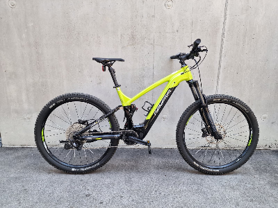 Grünes E-Bike mit Federung steht vor einer Betonwand.