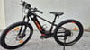 Ein schwarzes KTM E-Bike mit orangefarbenen Details steht vor einer Wand.