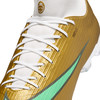 Goldene Fußballschuhe mit weißen Schnürsenkeln und grünem Streifen.