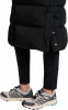 Detail von Frauenbeinen in schwarzen Hosen und Sportschuhen.