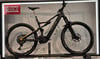 Ein schwarzes E-Mountainbike mit Federung und goldenen Details steht auf einem Ständer.