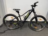Ein schwarzes E-Bike mit Federung und breiten Reifen steht auf einem dunklen Teppich.