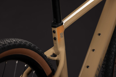 Rahmendetail eines Gravelbikes mit orangefarbenem Logo und Fahrradreifen. Rahmendetail eines Gravelbikes mit orangefarbenem Logo und Fahrradreifen.