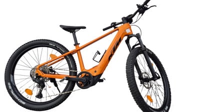Orange KTM E-Bike mit schwarzen Rädern und Lenker vor weißem Hintergrund.