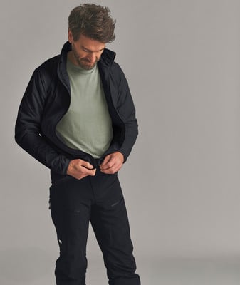 Ein Mann in schwarzer Kleidung schließt eine Jacke über einem hellgrünen T-Shirt. Ein Mann in schwarzer Kleidung schließt eine Jacke über einem hellgrünen T-Shirt.