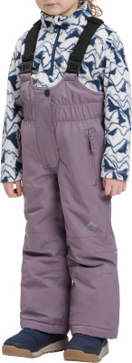 Ein Mädchen trägt eine lila Latzhose und einen Fleece-Pullover mit Bergmuster.