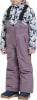 Ein Mädchen trägt eine lila Latzhose und einen Fleece-Pullover mit Bergmuster.