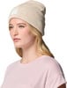 Ein Mädchen in einem rosa T-Shirt und einer beigen Mütze mit bunten Punkten.