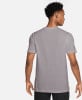 Ein Mann in einem grauen kurzärmeligen T-Shirt, von hinten gesehen.