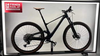 Schwarzes Mountainbike mit braunem Sattel und braunen Reifen auf einem Ständer.