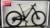 Schwarzes Mountainbike mit braunem Sattel und braunen Reifen auf einem Ständer.