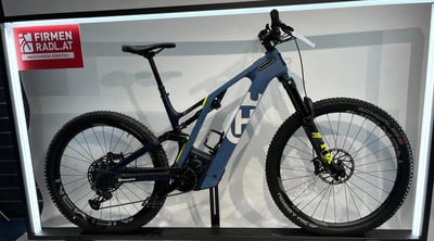 Ein blaues Mountain-E-Bike mit gelben Akzenten auf einem Ständer. Ein blaues Mountain-E-Bike mit gelben Akzenten auf einem Ständer.
