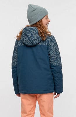 Mädchen in blauer Jacke mit Muster und orangefarbener Hose trägt eine Mütze. Mädchen in blauer Jacke mit Muster und orangefarbener Hose trägt eine Mütze.