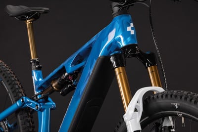 Ein blaues E-Mountainbike mit hochwertiger goldener Federgabel und Dämpfer.