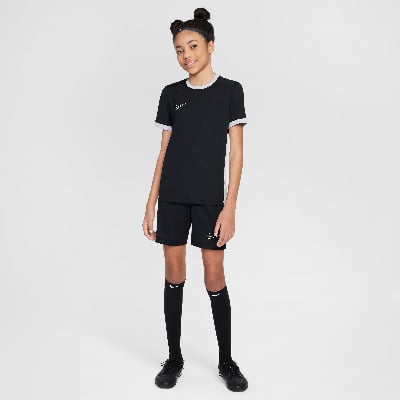 Ein Mädchen in Nike-Fußballkleidung posiert vor einem neutralen Hintergrund.