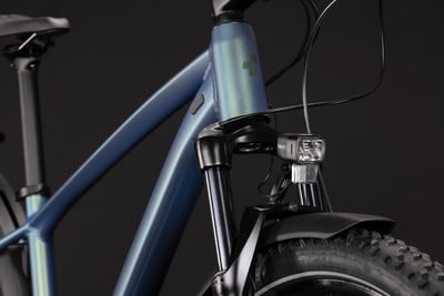 Detail eines Elektrofahrrads mit blauem Rahmen, Federung und Frontlicht.