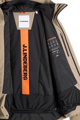 Die Innenseite einer beige Jacke mit schwarzem Futter und orangefarbenem Logo-Streifen. Die Innenseite einer beige Jacke mit schwarzem Futter und orangefarbenem Logo-Streifen.