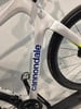 Detail eines weißen Fahrradrahmens mit Cannondale-Logo und schwarzem Rad.